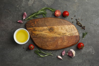 Photo of Cutting board, rosemary, garlic, oil and tomatoes on black table, flat lay. Space for text