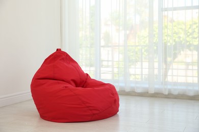 Red bean bag chair near window in room. Space for text