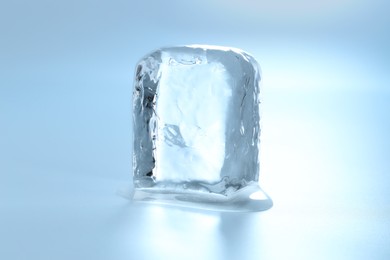 Photo of Cube of clear ice on light blue background