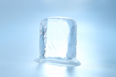 Cube of clear ice on light blue background