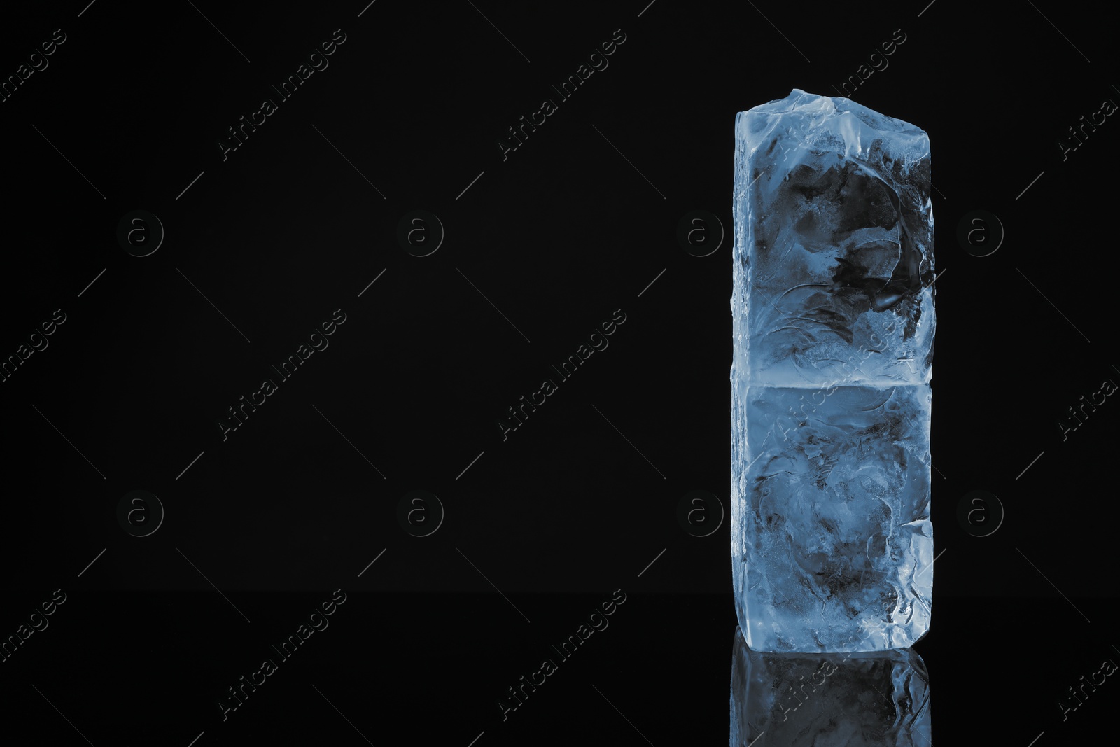 Photo of Blocks of clear ice on black mirror surface, space for text