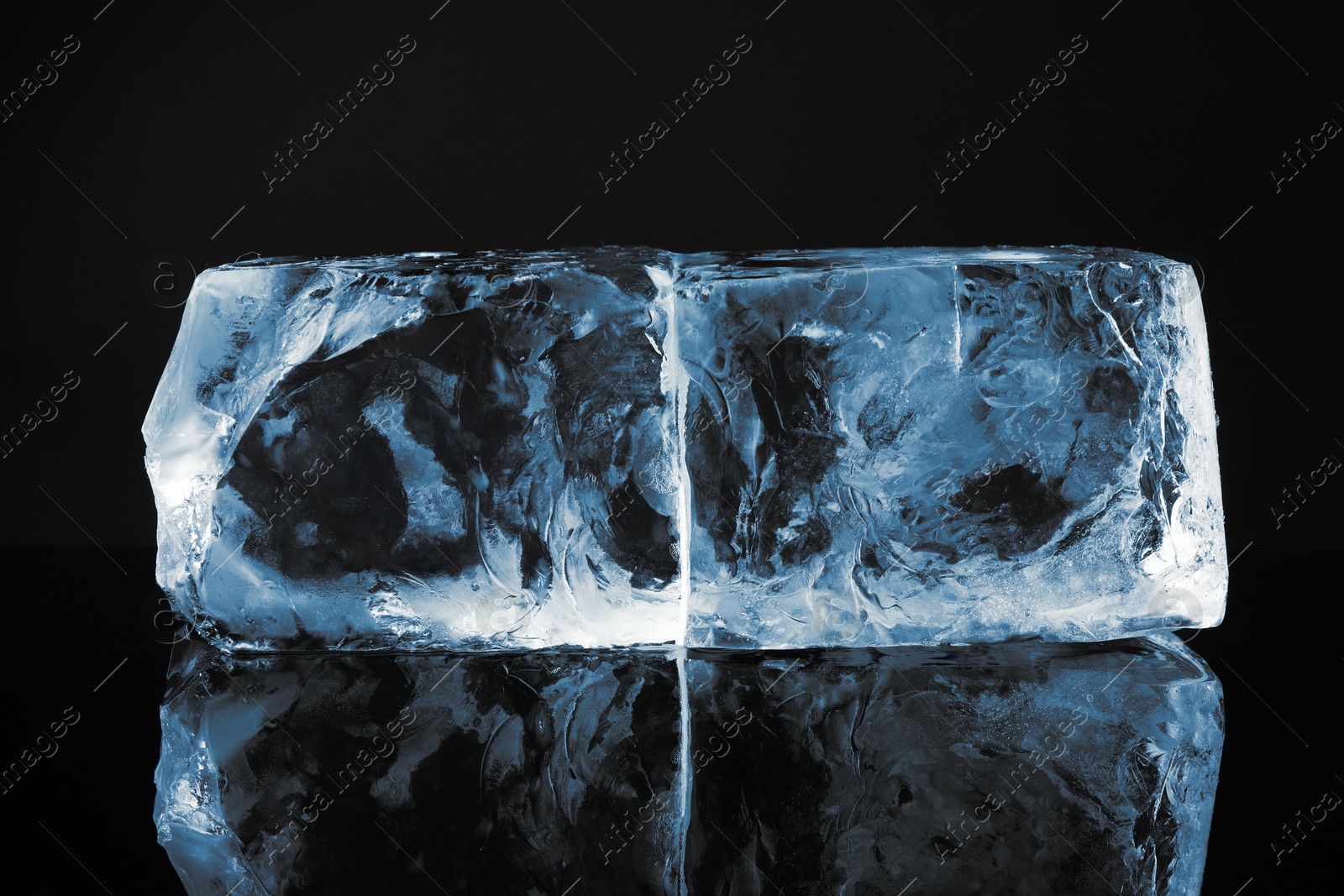 Photo of Blocks of clear ice on black mirror surface