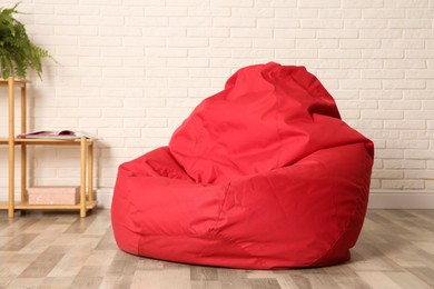 Red bean bag chair near white brick wall in room