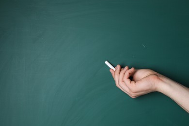 Teacher writing with chalk on green chalkboard, closeup. Space for text