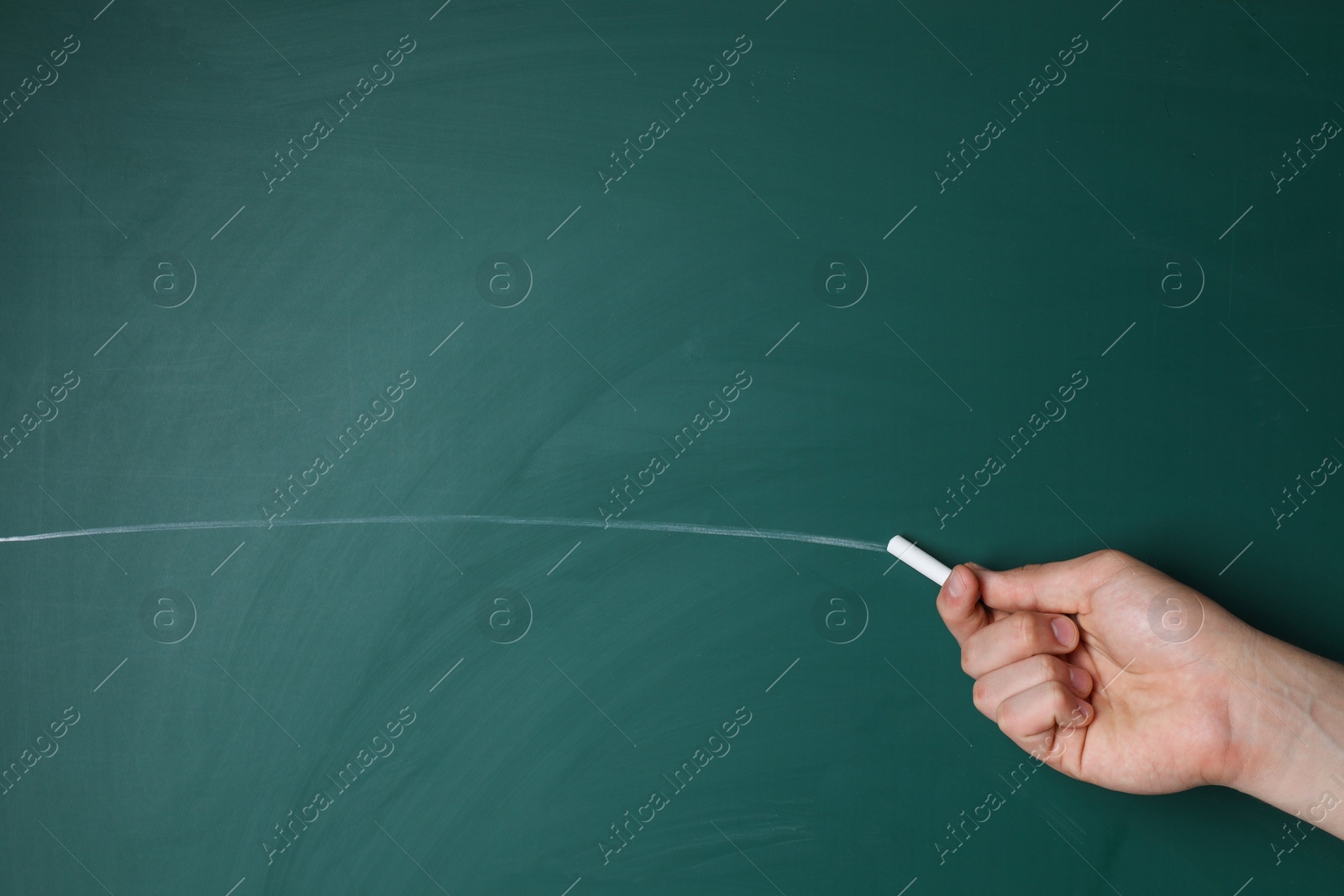 Photo of Teacher writing with chalk on green chalkboard, closeup. Space for text