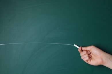 Teacher writing with chalk on green chalkboard, closeup. Space for text