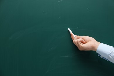 Photo of Teacher writing with chalk on green chalkboard, closeup. Space for text