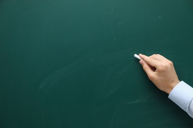 Teacher writing with chalk on green chalkboard, closeup. Space for text