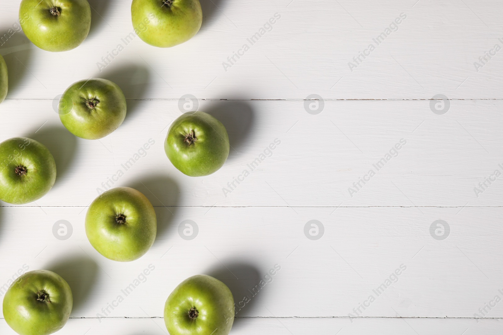 Photo of Fresh ripe green apples on white wooden table, flat lay. Space for text