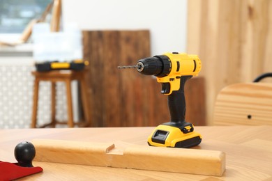 Photo of One cordless electric drill on wooden table in workshop