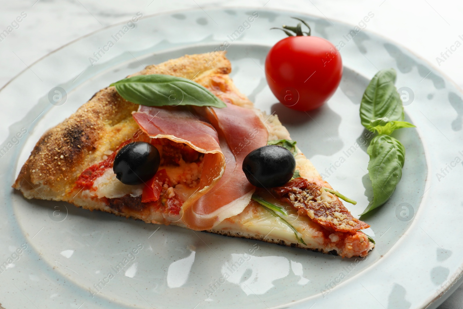 Photo of Tasty pizza with cured ham, olives, tomato and basil on plate, closeup