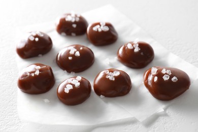 Tasty caramel candies and salt on white table, closeup