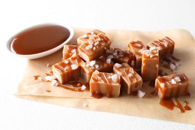 Photo of Tasty candies, caramel sauce and salt on white table