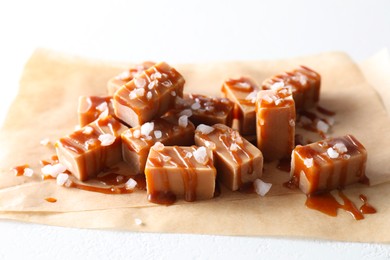 Tasty candies, caramel sauce and salt on white table, closeup