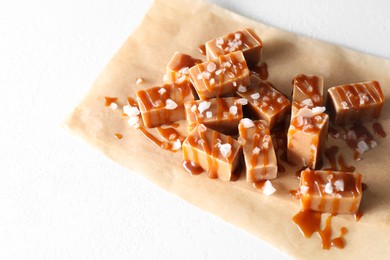 Photo of Tasty candies, caramel sauce and salt on white table