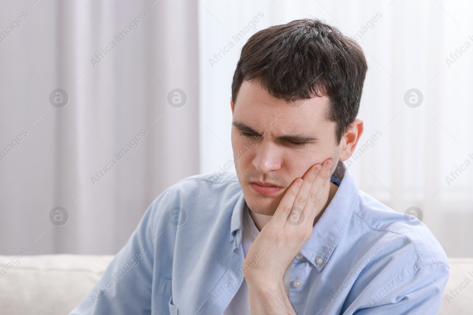 Photo of Sad man suffering from toothache at home