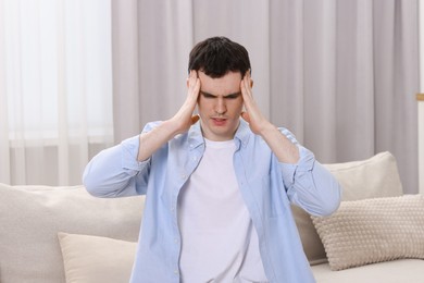 Man suffering from headache on sofa at home