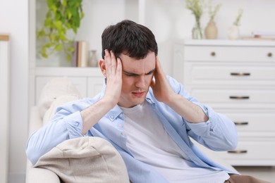 Photo of Man suffering from headache on sofa at home