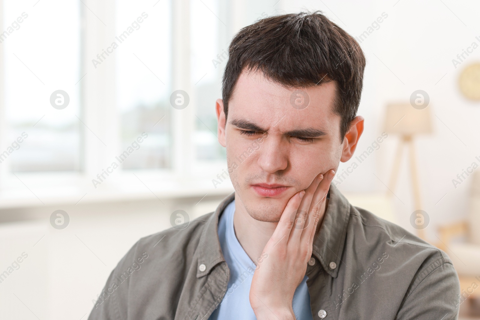 Photo of Sad man suffering from toothache at home
