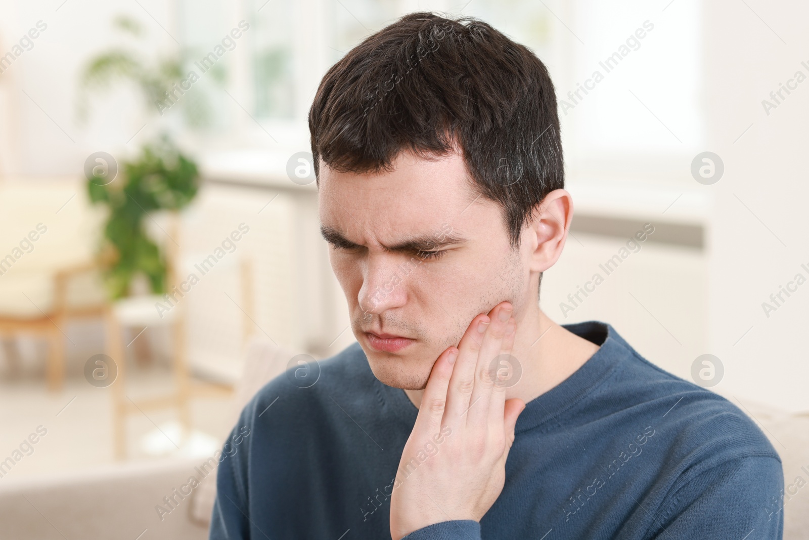 Photo of Sad man suffering from toothache at home, space for text