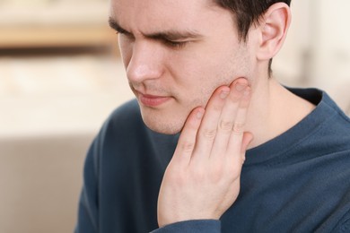 Photo of Sad man suffering from toothache at home