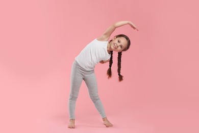 Photo of Cute little girl stretching on pink background