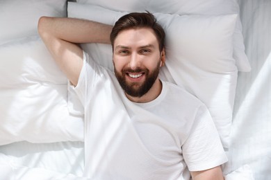 Photo of Handsome young man in bed at morning, top view