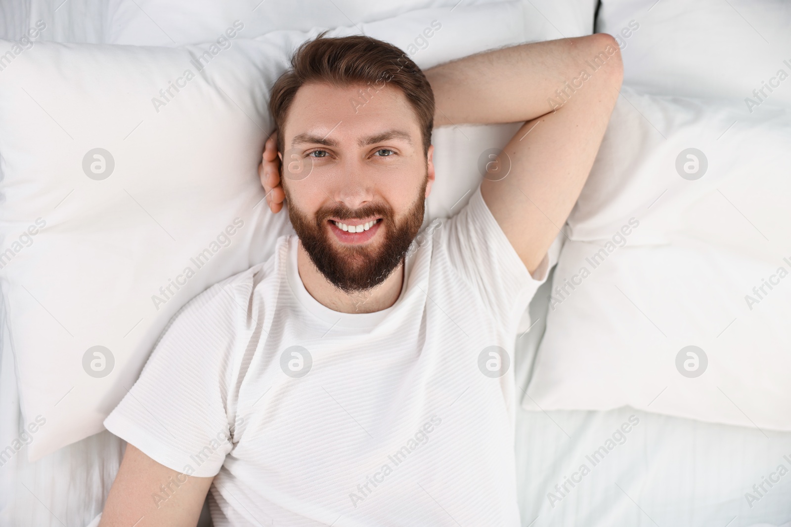 Photo of Handsome young man in bed at morning, top view