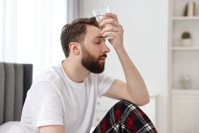 Photo of Young man suffering from headache on bed at morning