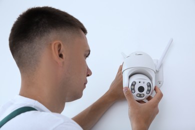 Technician installing CCTV camera on wall indoors