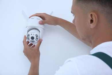 Technician installing CCTV camera on wall indoors, closeup