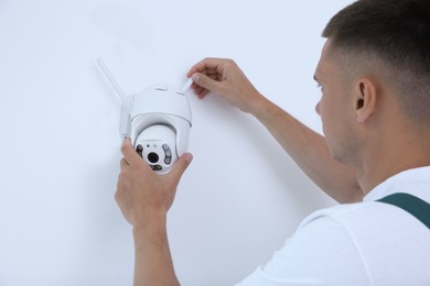 Photo of Technician installing CCTV camera on wall indoors