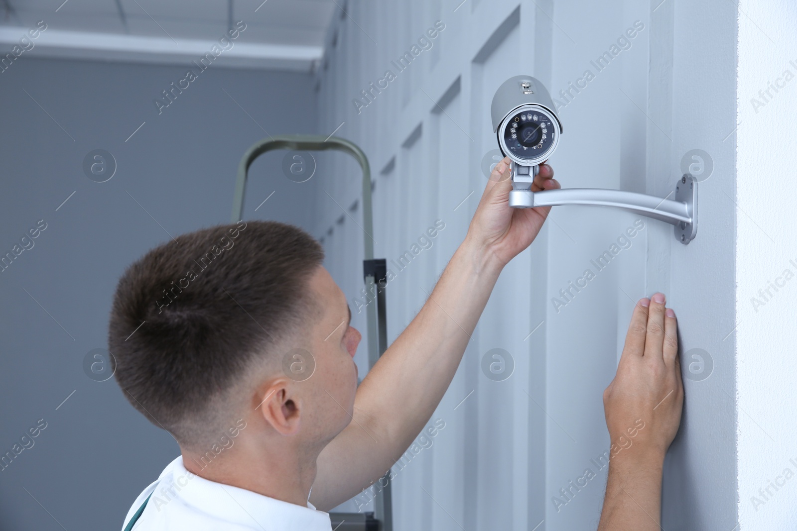 Photo of Technician installing CCTV camera on wall indoors