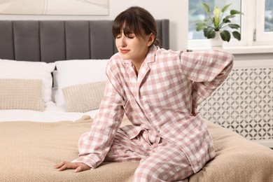 Photo of Upset woman suffering from back pain on bed at home
