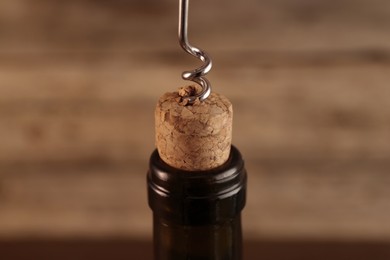 Photo of Wine bottle with corkscrew on blurred background, closeup