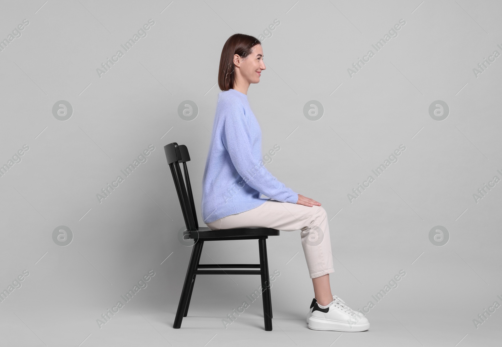 Photo of Woman with good posture sitting on chair against gray background