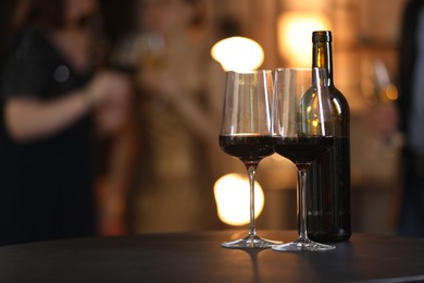 Photo of Tasty wine in glasses and bottle on black table indoors, selective focus