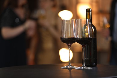 Tasty wine in glasses and bottle on black table indoors, selective focus