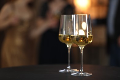 Photo of Tasty wine in glasses on black table indoors, selective focus