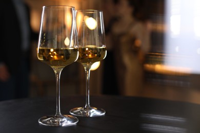 Photo of Different tasty wines in glasses on black table indoors, selective focus