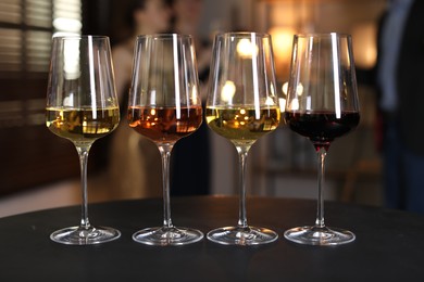 Different tasty wines in glasses on black table indoors, selective focus