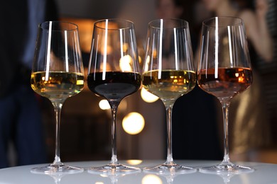 Photo of Different tasty wines in glasses on white table indoors, selective focus