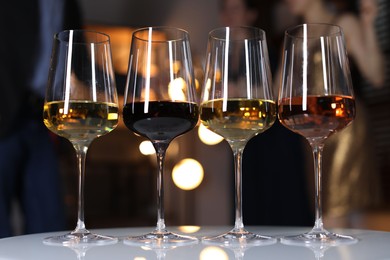 Different tasty wines in glasses on white table indoors, selective focus