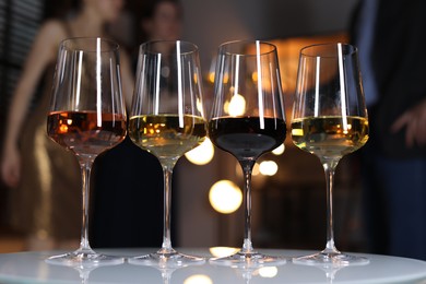 Photo of Different tasty wines in glasses on white table indoors, selective focus
