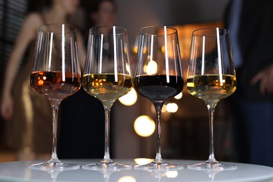 Different tasty wines in glasses on white table indoors, selective focus