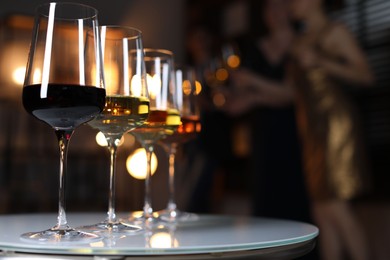 Different tasty wines in glasses on white table indoors, selective focus