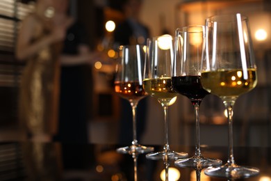 Different tasty wines in glasses on table indoors, selective focus