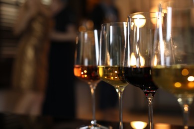 Different tasty wines in glasses on table indoors, selective focus