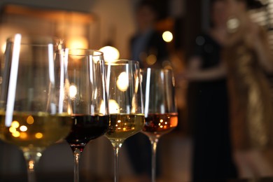 Photo of Different tasty wines in glasses indoors, selective focus