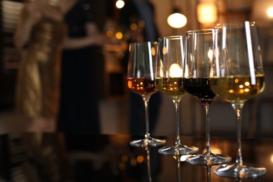 Different tasty wines in glasses on table indoors, selective focus